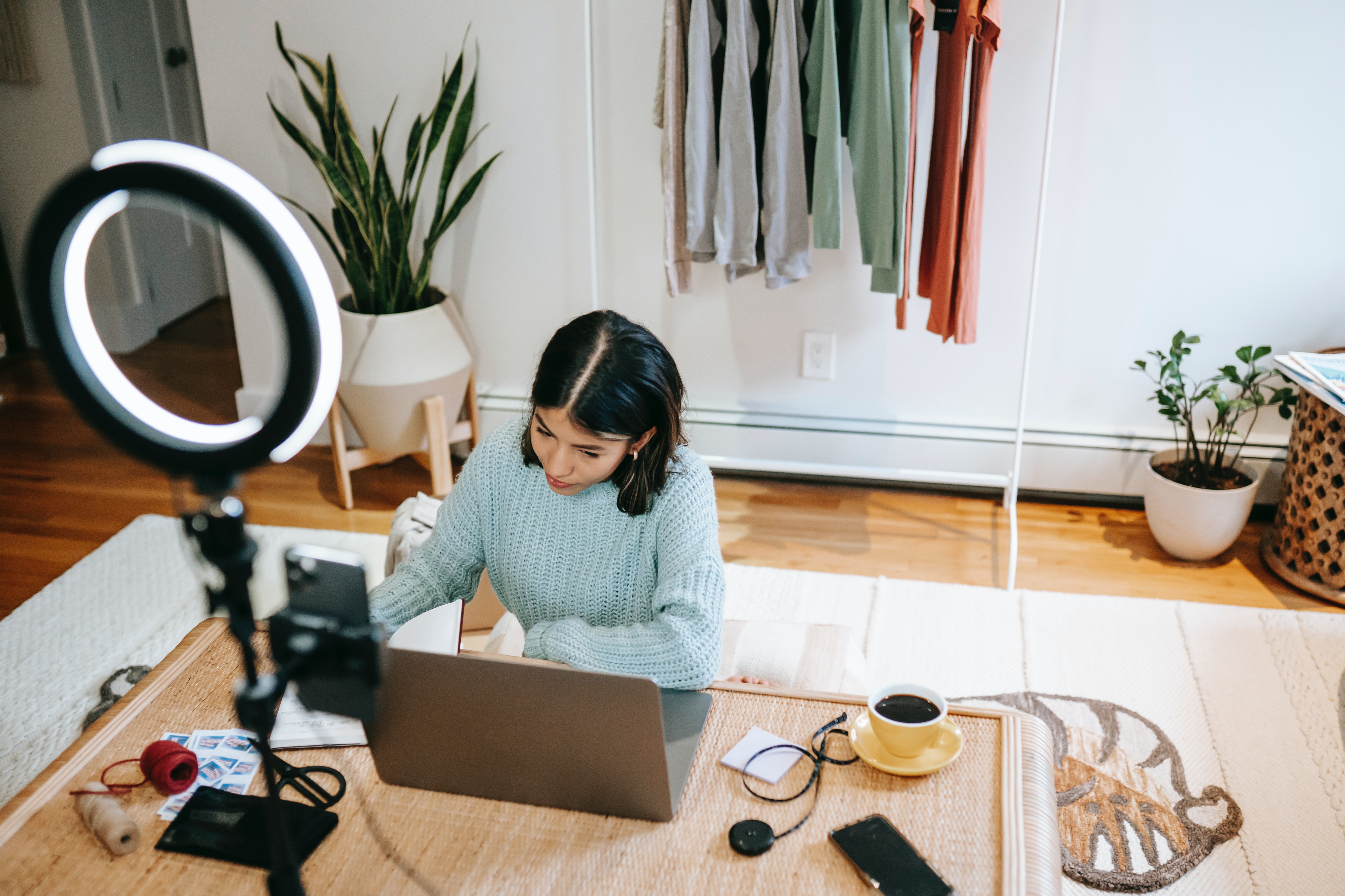 woman with ring light, cell phone, and laptop starting small business